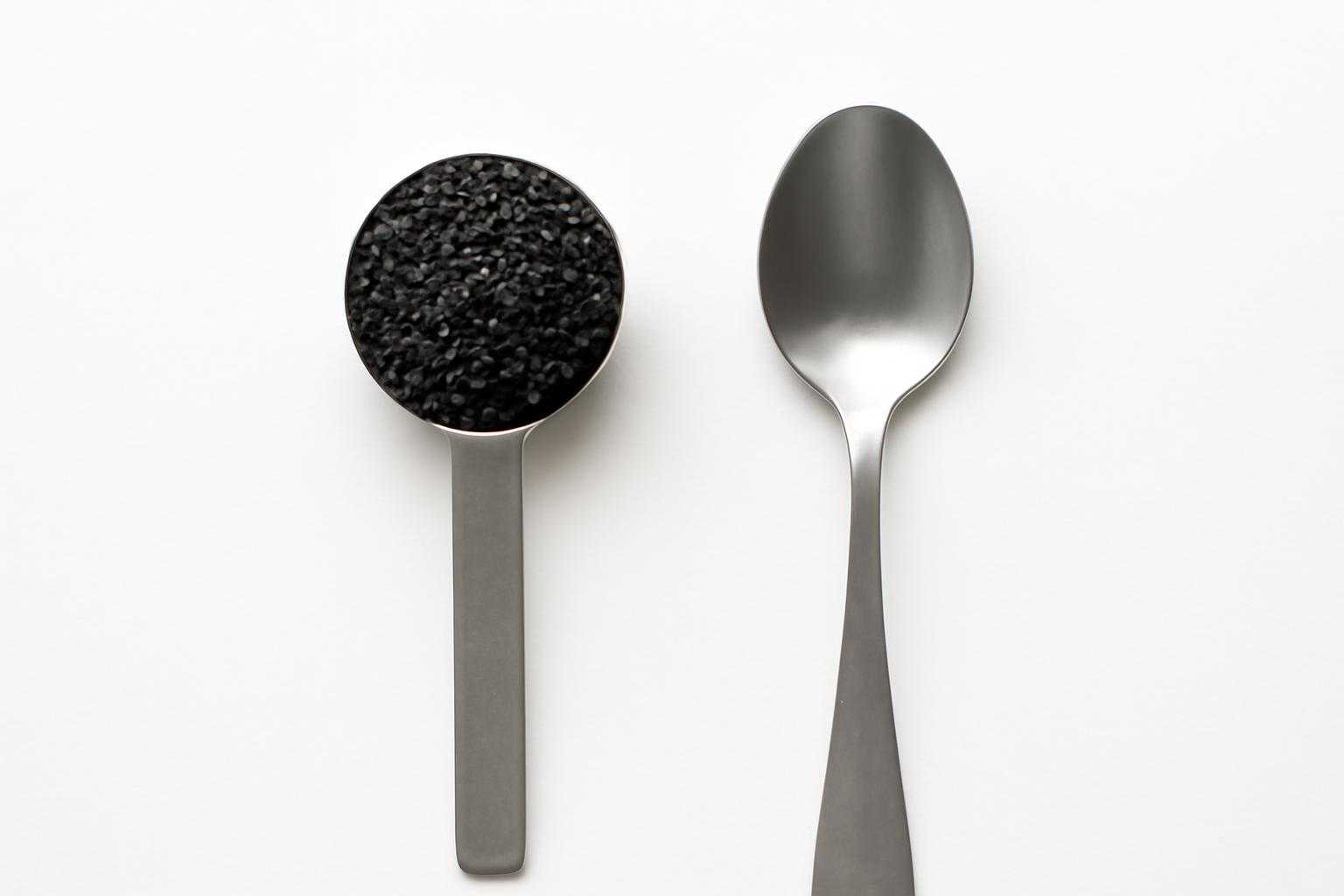 スプーンに盛られた黒ごまと、その量を示す計量スプーン