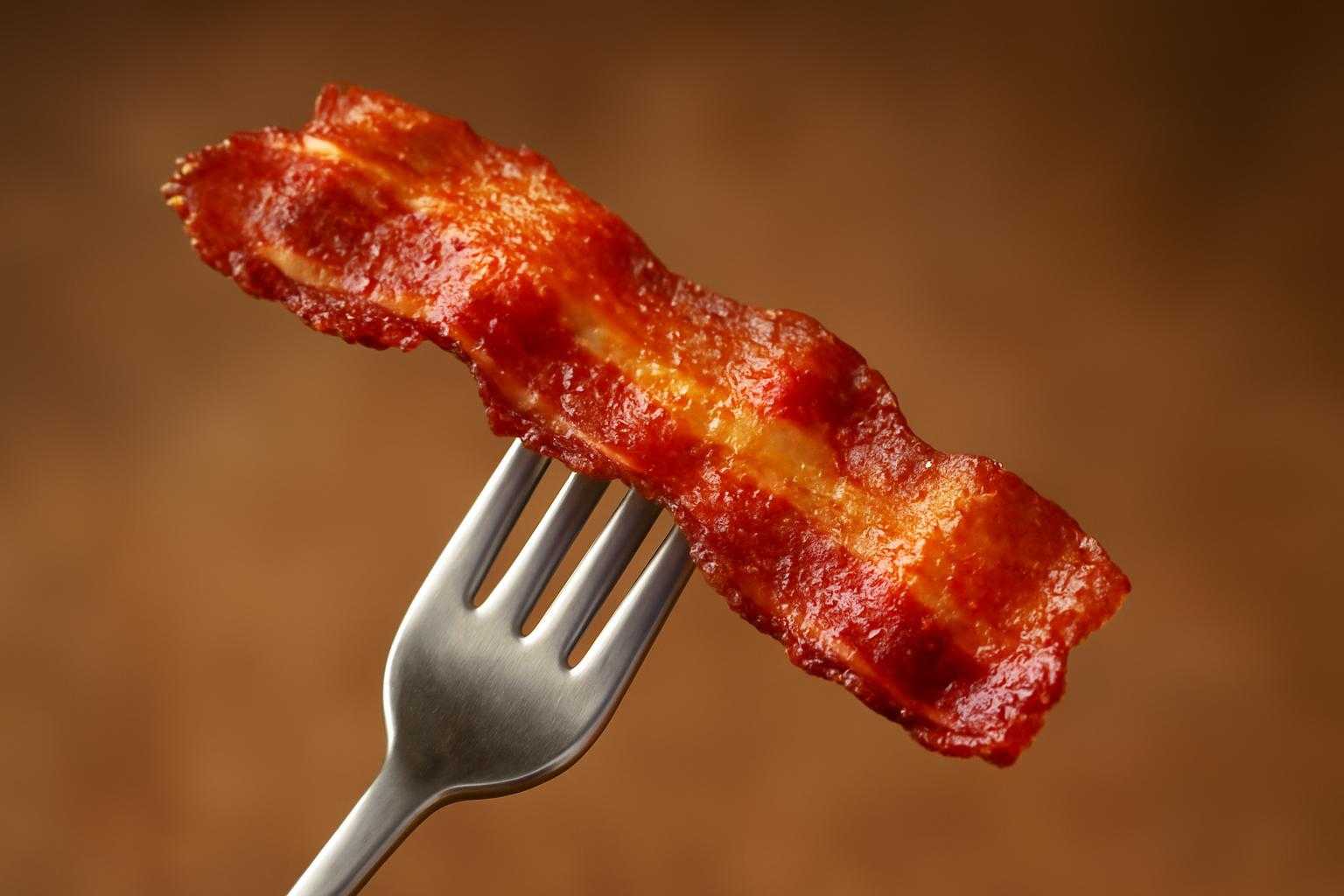 焼かれたカリッとしたベーコンをフォークで持った食べる場面